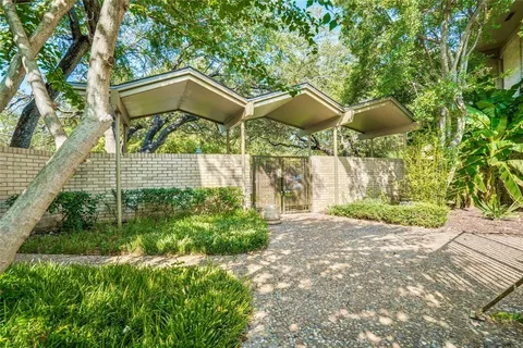 a backyard of a house with table and chairs under an umbrella