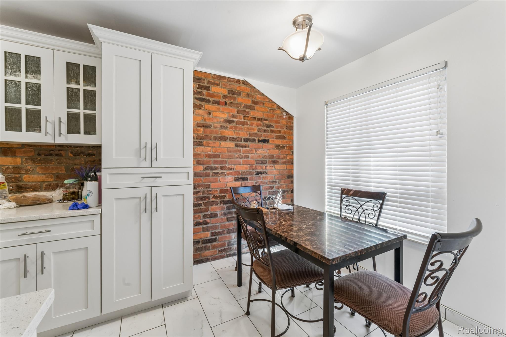 704 South Brady Road, Unit B Dearborn, MI 48124 - Photo 10 of 16 Exposed brick accent wall, white shaker cabinetry with brushed nickel hardware, light-toned tile flooring, and a flush-mount ceiling light fixture