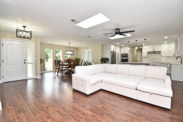 a view of a kitchen island stainless steel appliances wooden floor and living room view