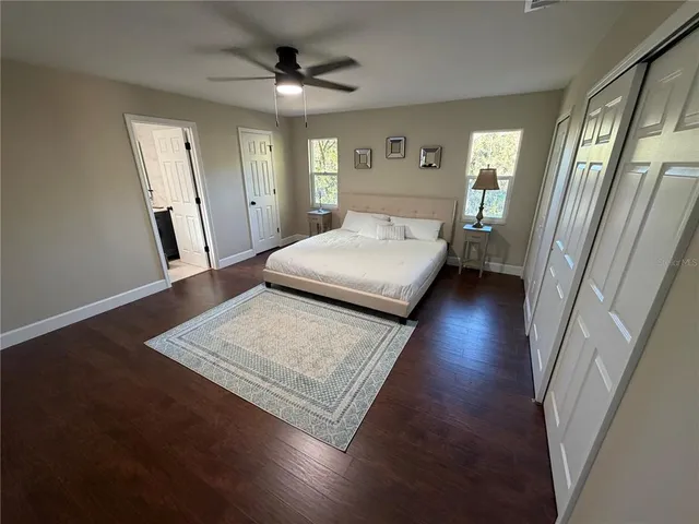 an empty room with wooden floor a ceiling fan and windows