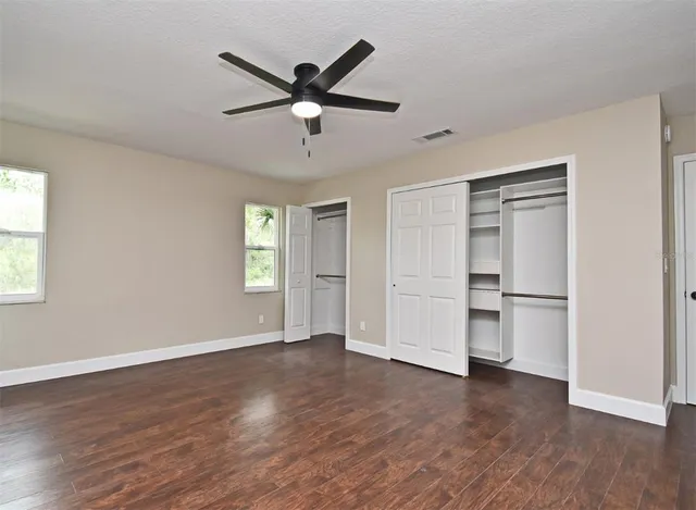 a walk in closet with wooden floor