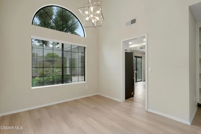 an empty room with wooden floor fan and windows