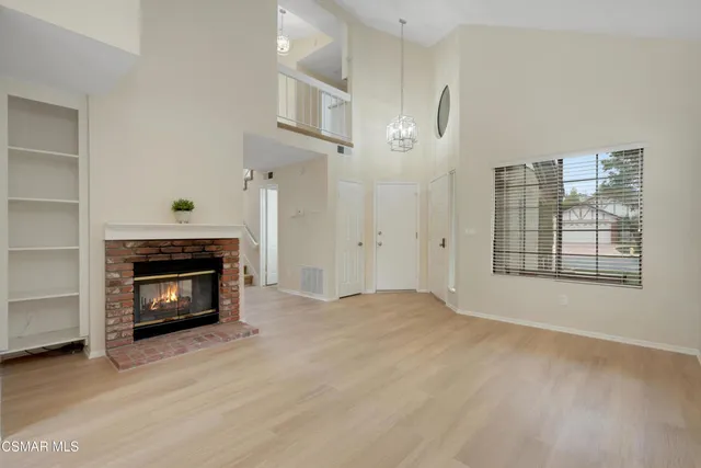 a view of an empty room with wooden floor fireplace and a window