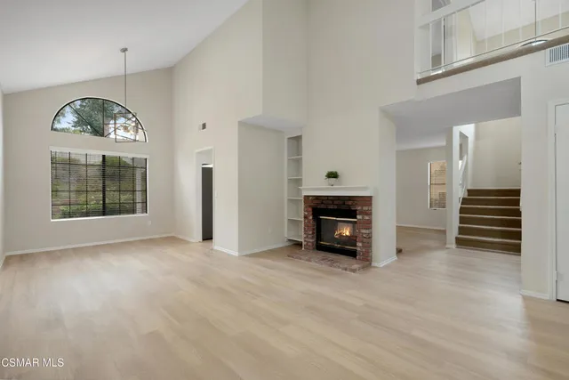 an empty room with windows and fireplace