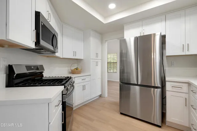 a kitchen with stainless steel appliances granite countertop a refrigerator stove a sink and dishwasher with wooden floor