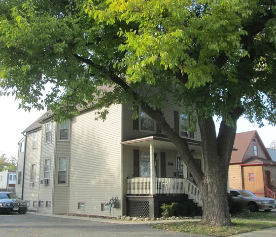 a large tree in front of a brick house