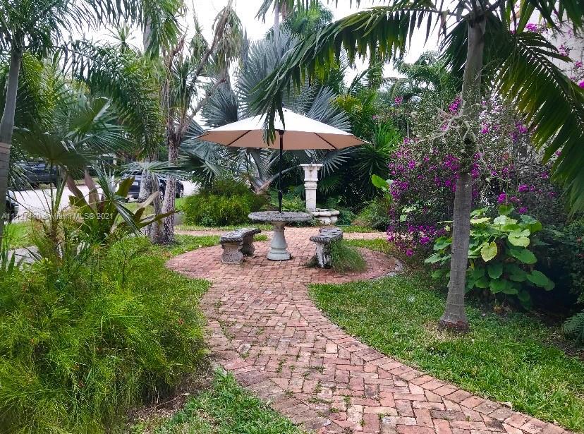 Hollywood Lakes North Lake Hollywood, FL 33019 - Photo 21 of 22 a view of a backyard with a patio table and chairs under an umbrella