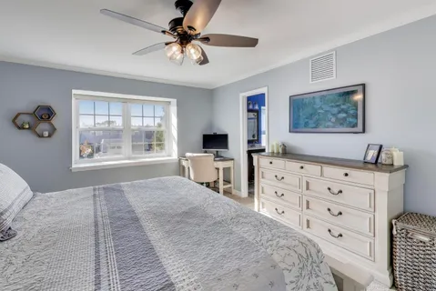 a bedroom with a bed a dresser and next to a window