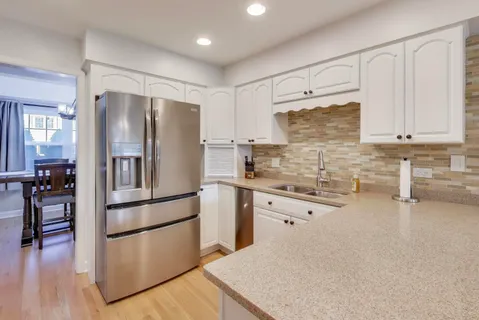 a kitchen with granite countertop white cabinets and stainless steel appliances