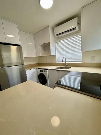 a kitchen with a sink a refrigerator and cabinets