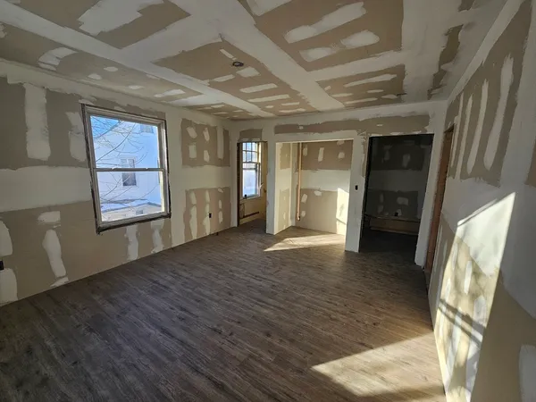 a view of an empty room with window and wooden floor