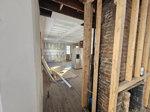 an empty room with wooden floor fireplace and windows