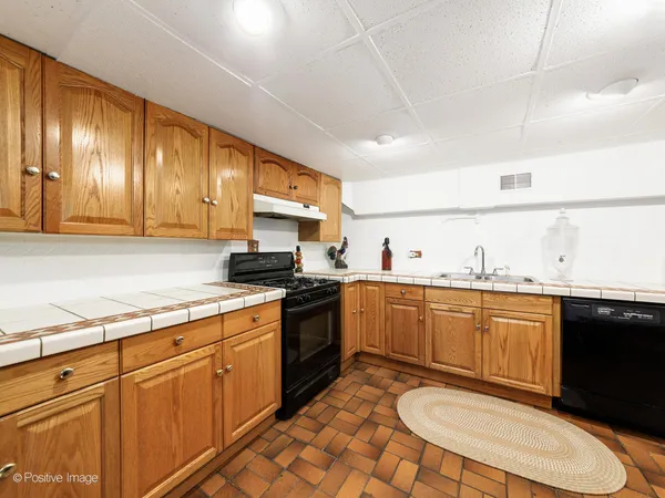 a kitchen with granite countertop stainless steel appliances a sink a stove a refrigerator cabinets and a dining table
