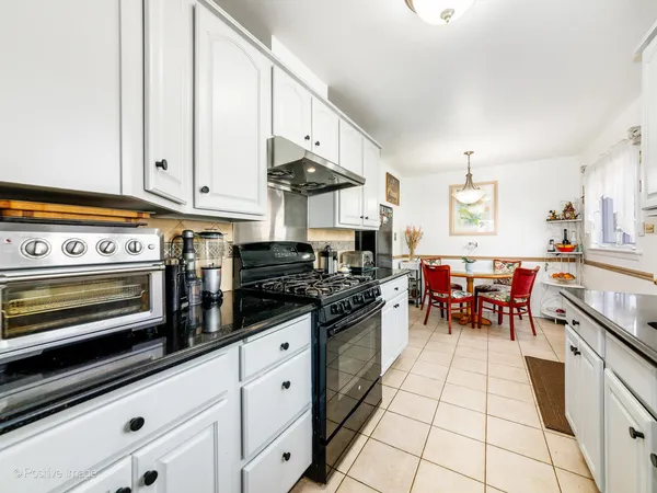 a kitchen with stainless steel appliances granite countertop a stove a sink and white cabinets