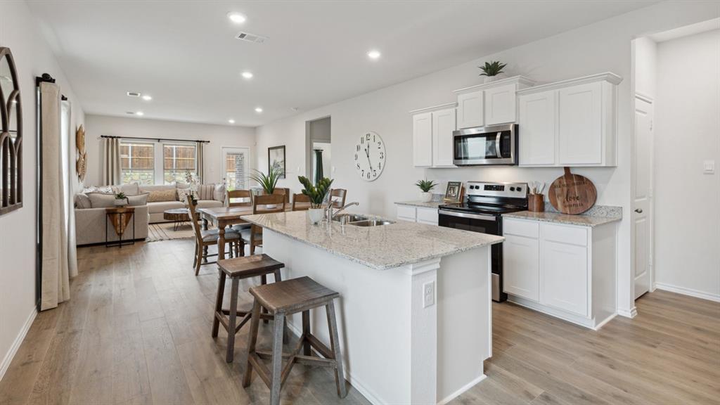 126 Pheasant Run Road Terrell, TX 75160 - Photo 5 of 26 Kitchen with stainless steel appliances, white cabinetry, light stone countertops, a breakfast bar area, and recessed lighting
