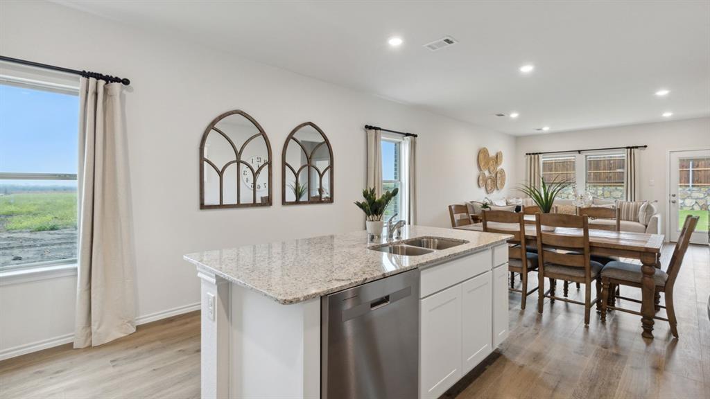 126 Pheasant Run Road Terrell, TX 75160 - Photo 6 of 26 Kitchen featuring white cabinetry, stainless steel dishwasher, light stone counters, light wood-style flooring, and an island with sink