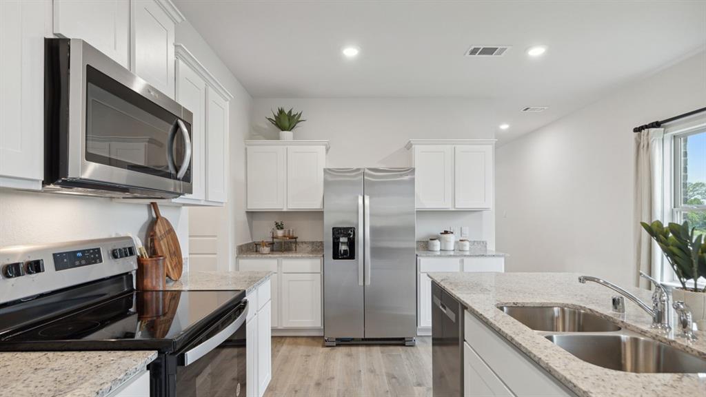 126 Pheasant Run Road Terrell, TX 75160 - Photo 8 of 26 Kitchen featuring stainless steel appliances, white cabinetry, recessed lighting, light wood-style flooring, and light stone counters