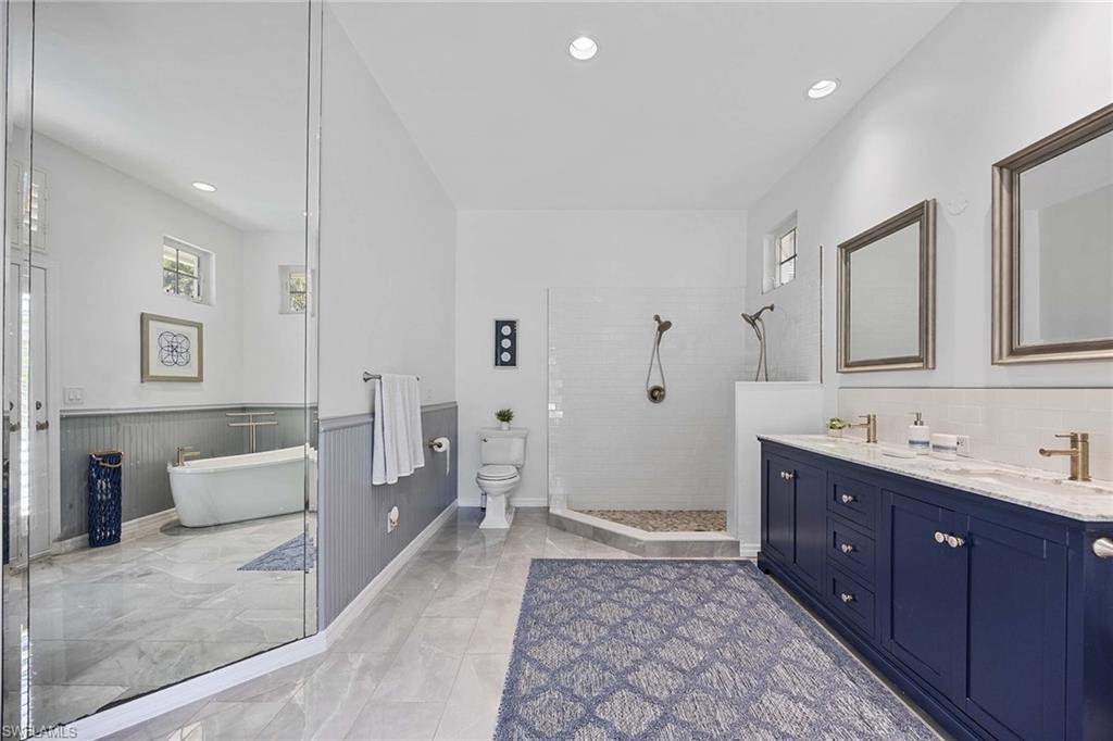 707 Portside Drive Naples, FL 34103 - Photo 24 of 35 a spacious bathroom with a double vanity sink a large mirror and a bathtub