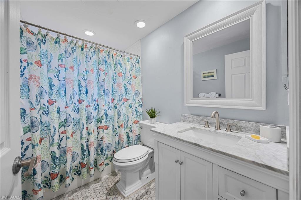 707 Portside Drive Naples, FL 34103 - Photo 27 of 35 a bathroom with a granite countertop sink a toilet and a mirror