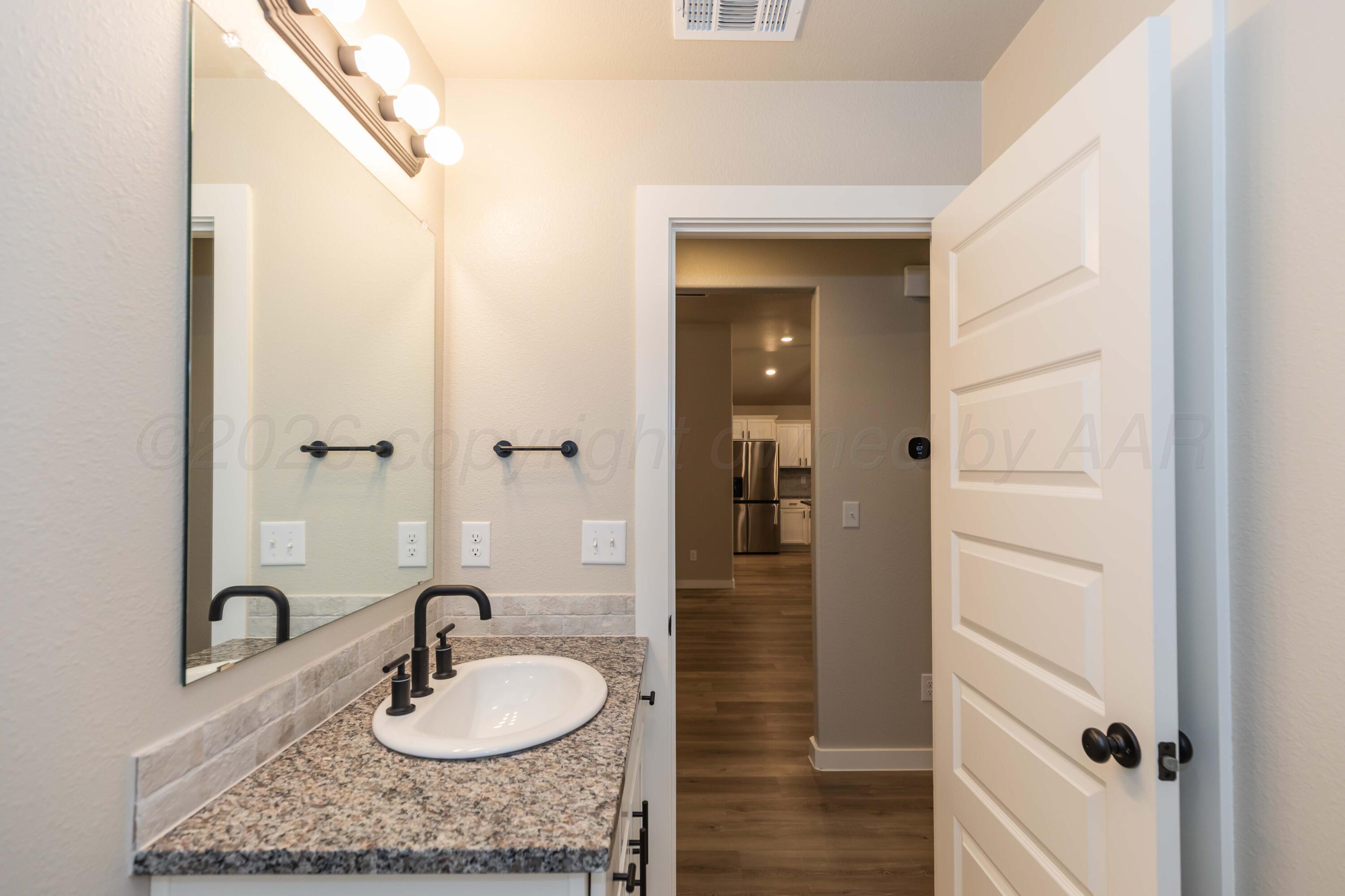 1807 Moon River Road Amarillo, TX 79118 - Photo 22 of 37 a bathroom with a granite countertop sink a mirror and shower