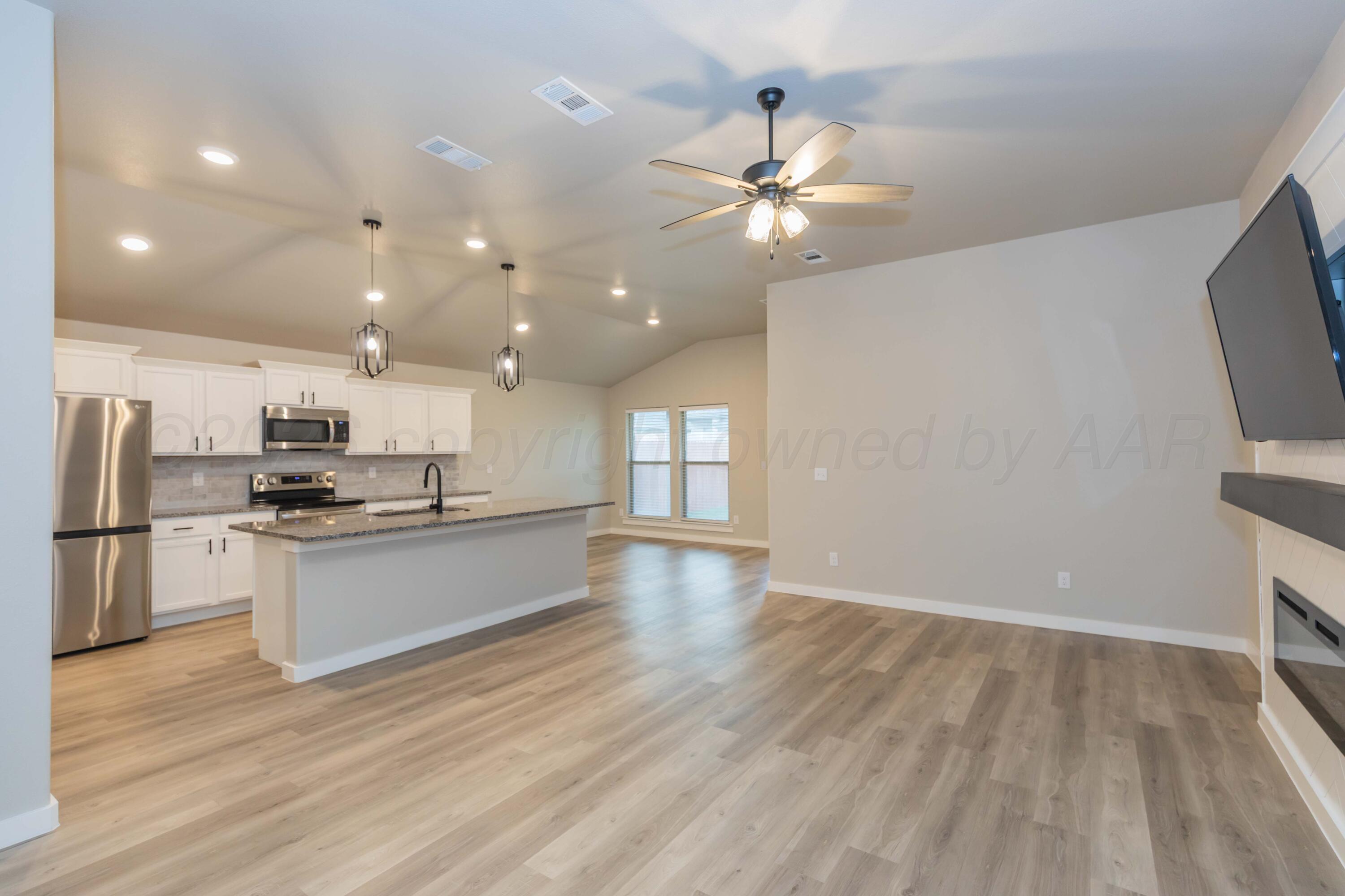 1807 Moon River Road Amarillo, TX 79118 - Photo 8 of 37 a large kitchen with kitchen island a stove a sink a refrigerator and a fireplace with wooden floor
