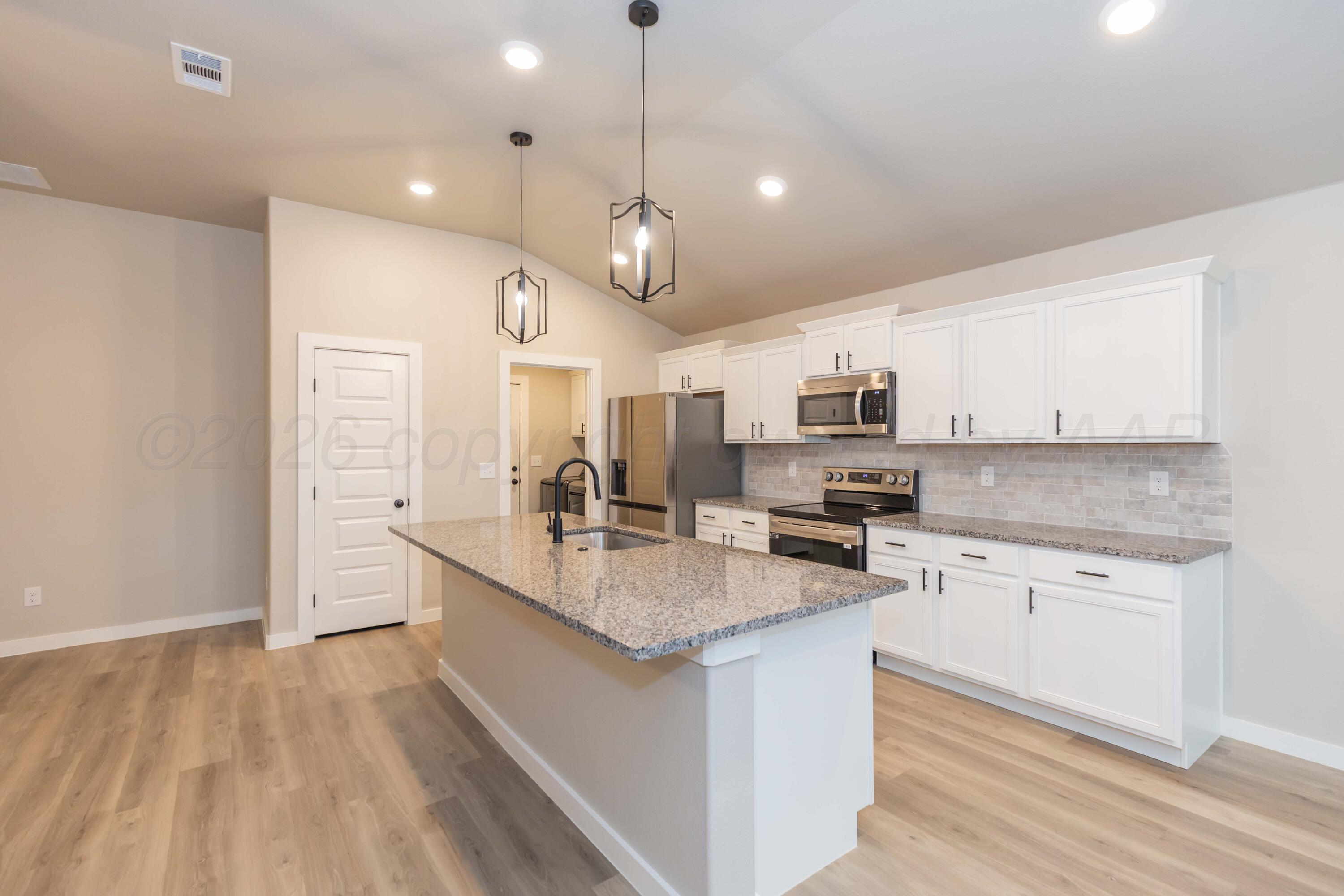 1807 Moon River Road Amarillo, TX 79118 - Photo 10 of 37 a large kitchen with granite countertop a large center island a sink dishwasher and a stove with wooden floor