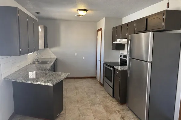 a kitchen with stainless steel appliances granite countertop a refrigerator a sink and a refrigerator