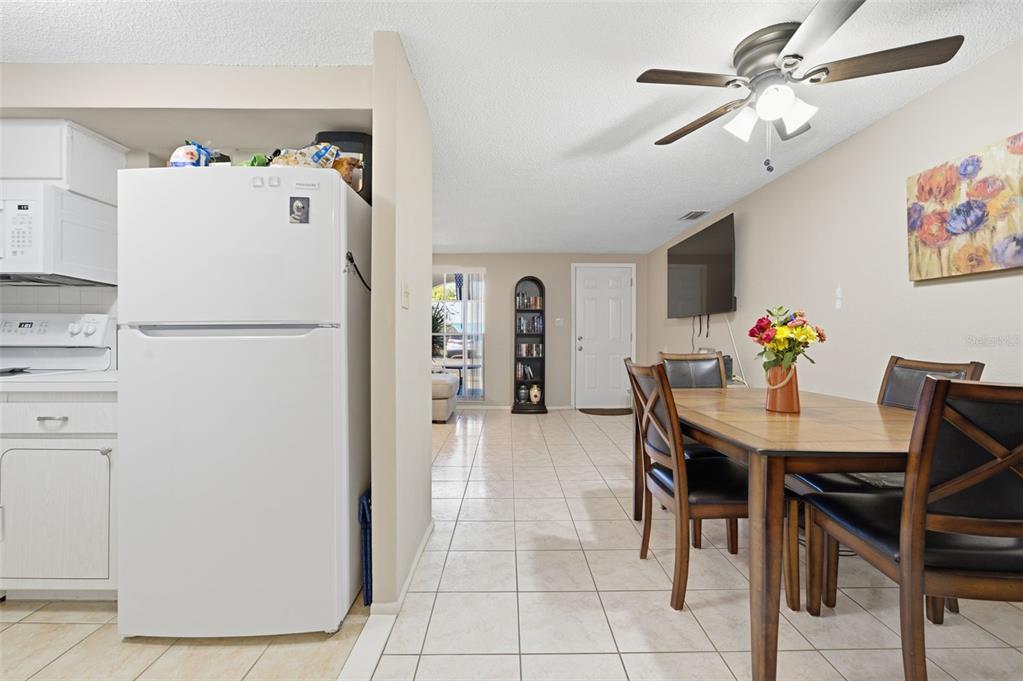 4218 Terrapin Place, Unit D New Port Richey, FL 34652 - Photo 13 of 34 a white kitchen with a refrigerator a stove a dining table and chairs