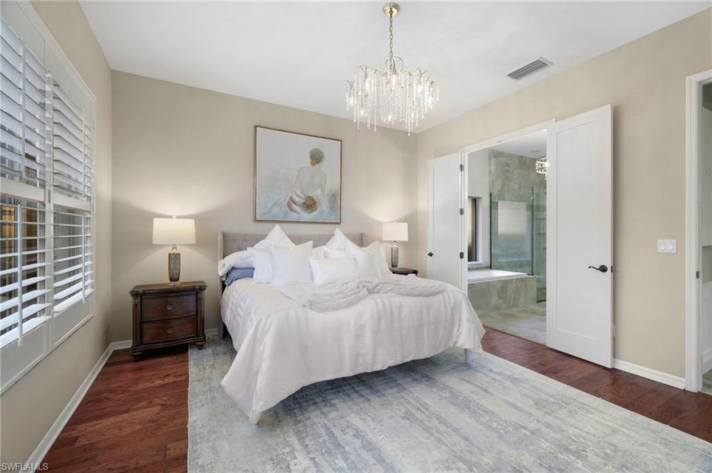 10071 St Moritz Drive Miromar Lakes, FL 33913 - Photo 13 of 45 a spacious bedroom with a bed and a chandelier