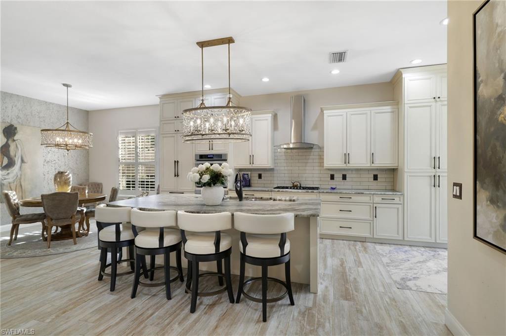 10071 St Moritz Drive Miromar Lakes, FL 33913 - Photo 8 of 45 a kitchen with stainless steel appliances a dining table chairs and wooden floor