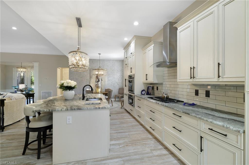 10071 St Moritz Drive Miromar Lakes, FL 33913 - Photo 10 of 45 a large kitchen with kitchen island granite countertop a sink a stove and a wooden floors