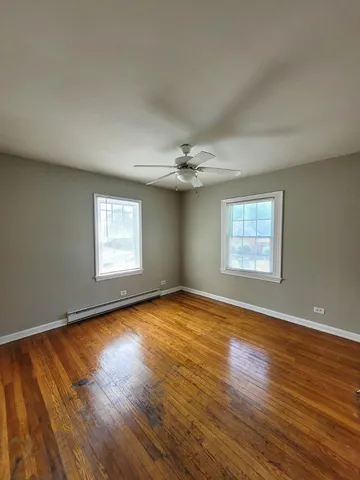 an empty room with wooden floor chandelier and windows