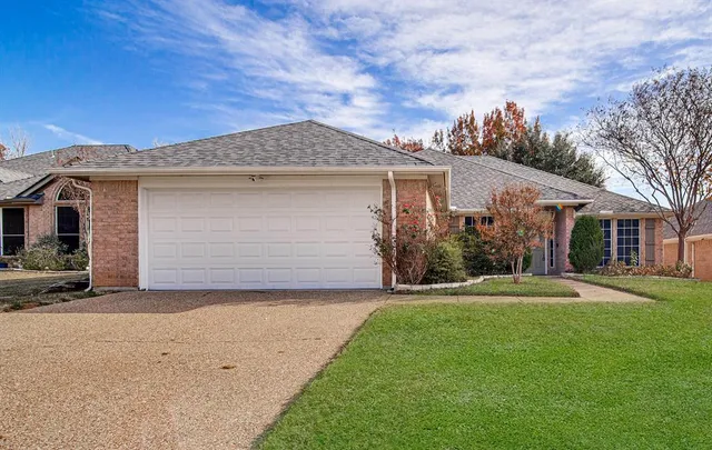 a front view of house with yard and trees in the background