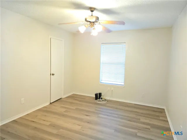 a view of a room with wooden floor and a ceiling fan