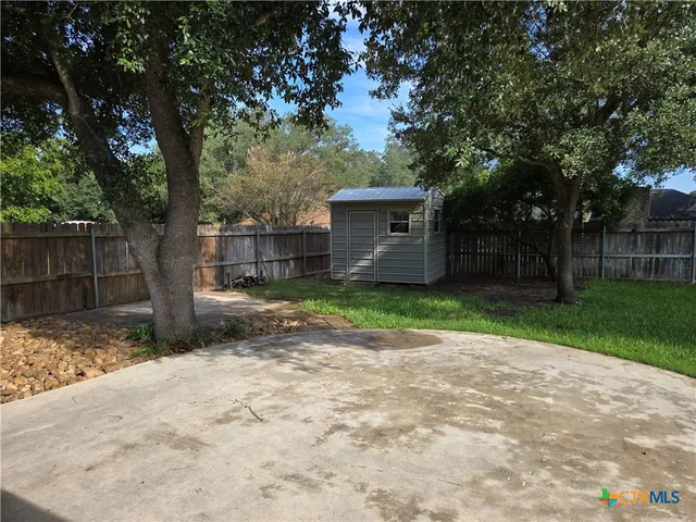 a view of a yard with a large tree and wooden fence
