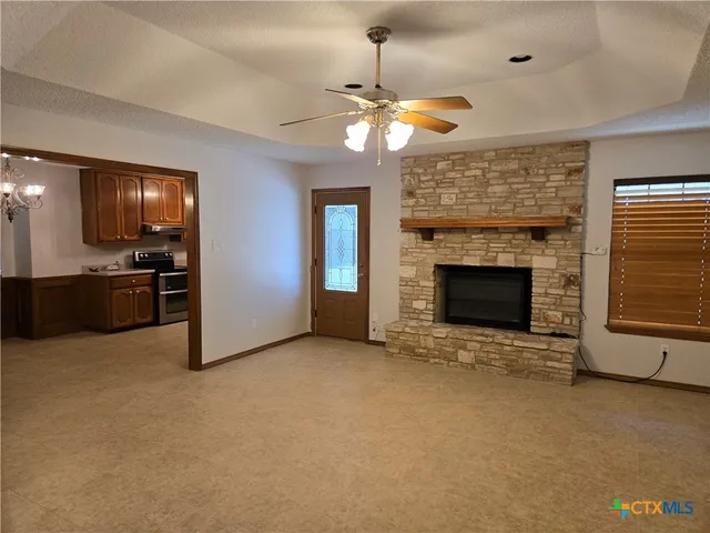 an empty room with fireplace cabinet and windows