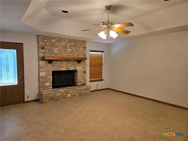 an empty room with a fireplace and chandelier fan