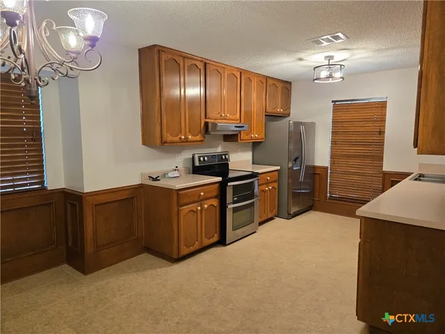 a kitchen with stainless steel appliances granite countertop a sink refrigerator and cabinets