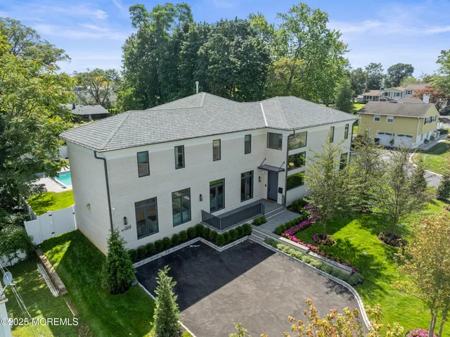 an aerial view of a house with yard and trees in the background