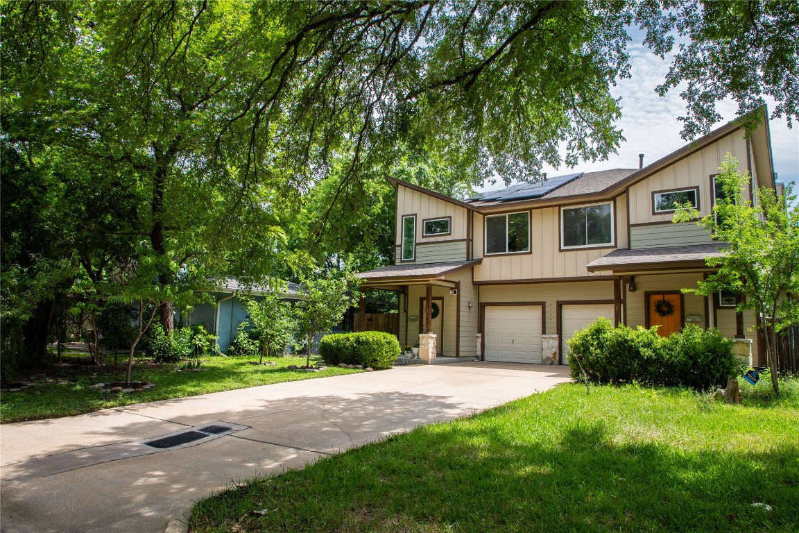 3407 Banton Road, Unit A Austin, TX 78722 - Photo 2 of 39 View of front of home featuring driveway, solar panels, board and batten siding, an attached garage, and a front yard