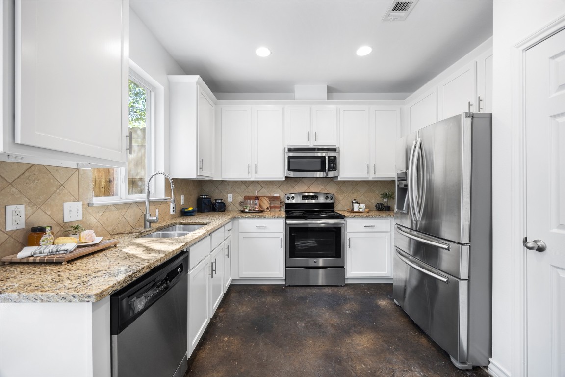 3407 Banton Road, Unit A Austin, TX 78722 - Photo 30 of 39 Kitchen featuring stainless steel appliances, white cabinets, light stone countertops, concrete floors, and recessed lighting