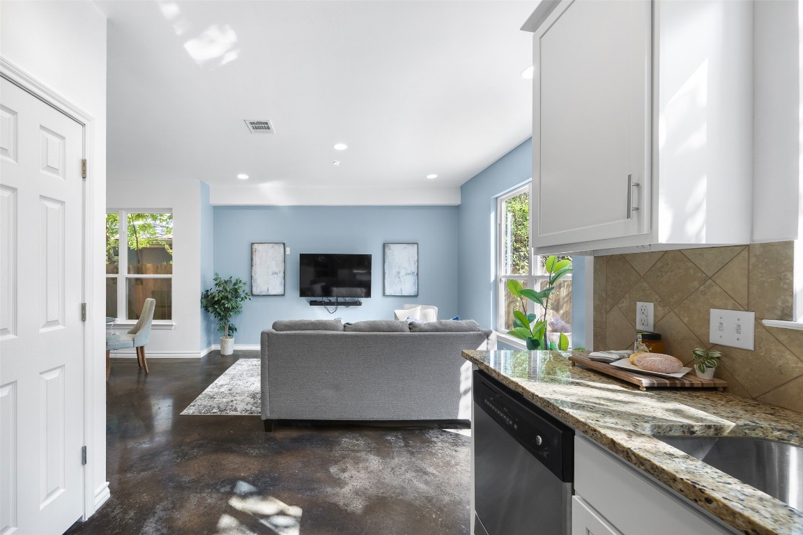 3407 Banton Road, Unit A Austin, TX 78722 - Photo 32 of 39 Kitchen with light stone counters, white cabinetry, finished concrete flooring, dishwasher, and backsplash
