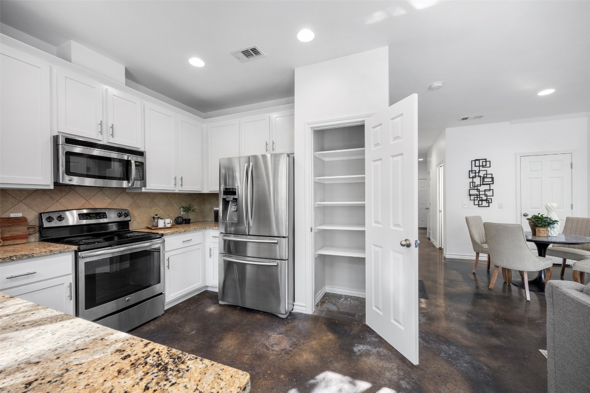 3407 Banton Road, Unit A Austin, TX 78722 - Photo 33 of 39 Kitchen featuring stainless steel appliances, concrete floors, white cabinetry, tasteful backsplash, and light stone countertops