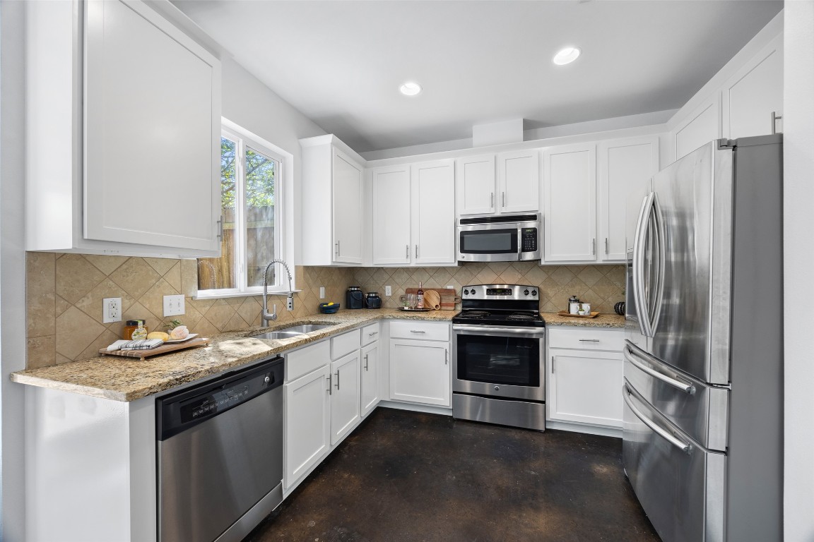 3407 Banton Road, Unit A Austin, TX 78722 - Photo 34 of 39 Kitchen with appliances with stainless steel finishes, white cabinets, light stone countertops, finished concrete flooring, and tasteful backsplash