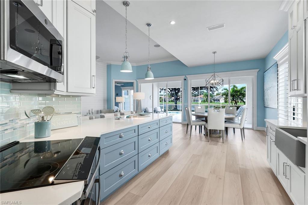 3787 Whidbey Way Naples, FL 34119 - Photo 4 of 50 a kitchen with stainless steel appliances granite countertop a sink dishwasher a stove and a microwave oven with wooden floor