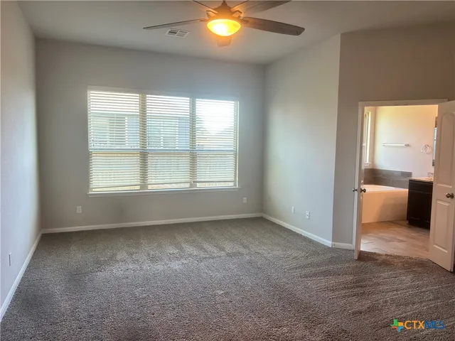 a view of an empty room with a window and a kitchen