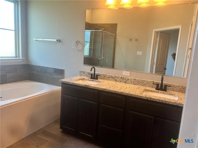 a bathroom with a granite countertop bathtub sink double and mirror