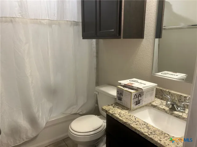 a bathroom with a granite countertop sink a toilet and a mirror