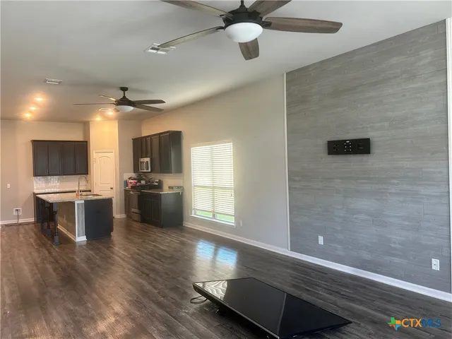 a view of a room with kitchen island stainless steel appliances wooden floor and windows