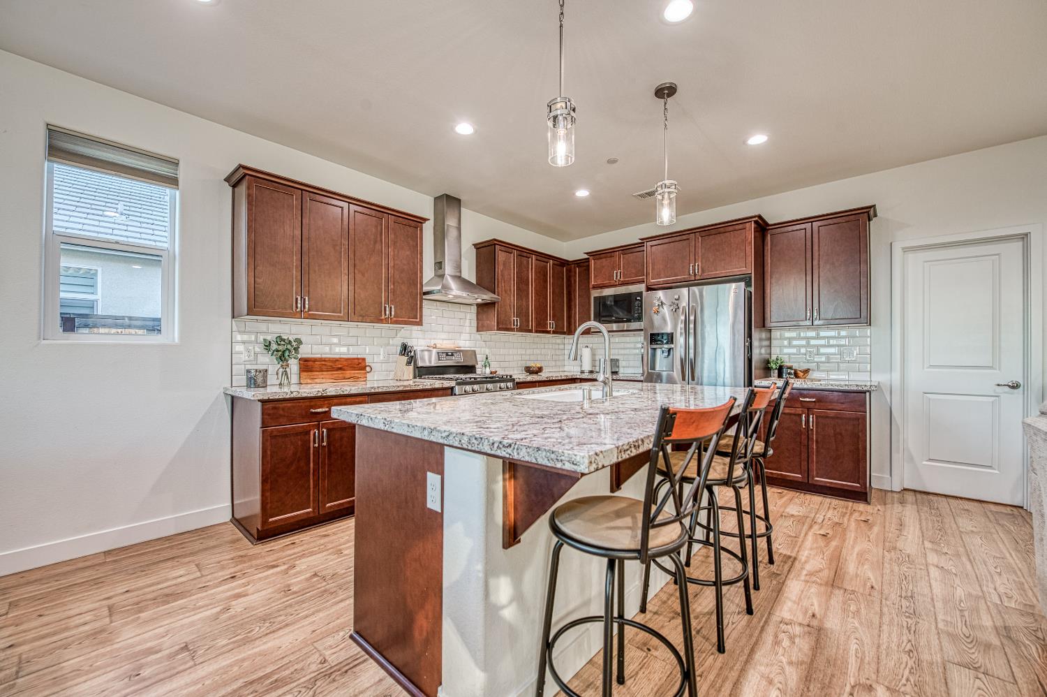 4534 Hillside Road Madera, CA 93636 - Photo 31 of 92 a kitchen with stainless steel appliances granite countertop a stove top oven a refrigerator a sink and dishwasher with wooden floor